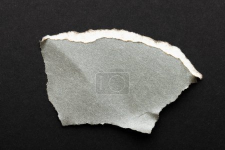 Téléchargez les photos : Déchiré morceau de papier gris avec de l'espace de copie sur fond noir. Texture abstraite du papier fond et concept de communication. - en image libre de droit