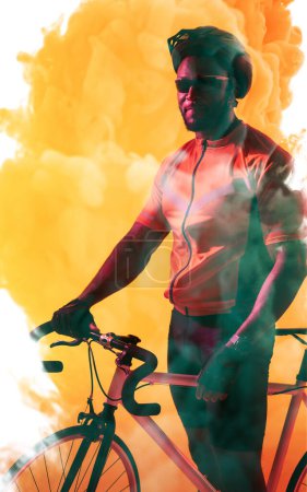 Téléchargez les photos : Athlète afro-américain portant un casque et des lunettes debout avec un vélo sur fond fumé. Espace de copie, composite, sport, cyclisme, course, compétition et concept abstrait. - en image libre de droit
