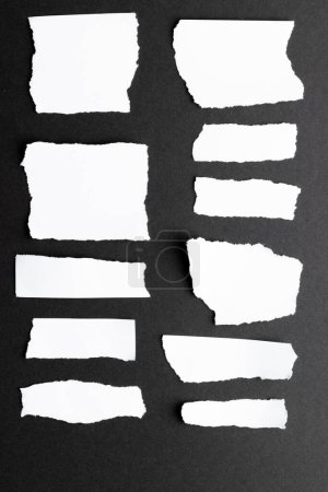 Zerrissene Stücke weißen Papiers mit Kopierraum auf schwarzem Hintergrund. Abstraktes Papier Textur Hintergrund und Kommunikationskonzept.