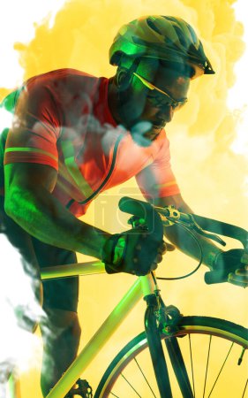 Photo for African american male cyclist wearing helmet and eyewear riding bike over yellow smoky background. Copy space, composite, sport, cycling, racing, competition and abstract concept. - Royalty Free Image