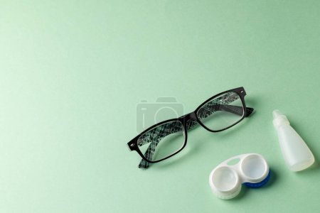 Photo for Composition of glasses with eye drops and contact lenses on green background. Medicine, healthcare, science and copy space concept, digital composite image. - Royalty Free Image