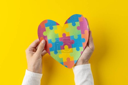 Photo for Composition of hands holding jigsaw puzzle heart on yellow background with copy space. Medical services, healthcare and health awareness concept. - Royalty Free Image