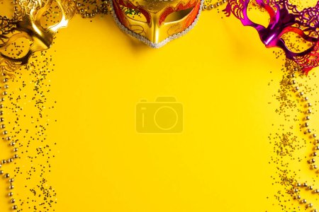 Téléchargez les photos : Composition de perles de mardi gras colorées et masques de carnaval sur fond jaune avec espace de copie. Fête, célébration et concept de carnaval. - en image libre de droit
