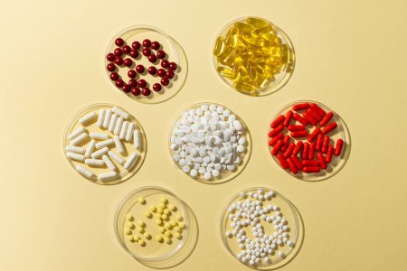 Photo for Composition of a variety of pills in glass dishes on yellow background with copy space. Medicine, medical services, healthcare and health awareness concept. - Royalty Free Image
