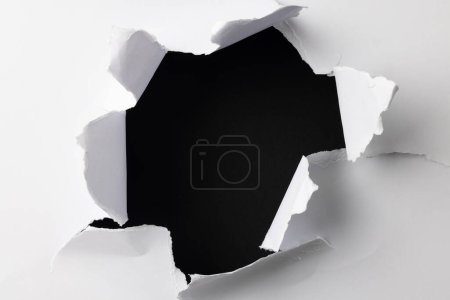 Aufgerissenes Stück weißes Papier mit Kopierraum auf schwarzem Hintergrund. Abstraktes Papier Textur Hintergrund und Kommunikationskonzept.