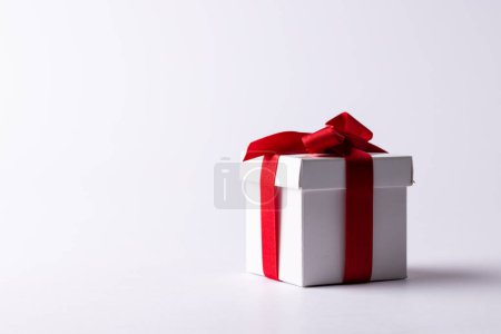 Téléchargez les photos : Boîte cadeau blanche attachée avec ruban rouge, sur fond blanc avec espace de copie. Saint Valentin, amour, romance et concept de célébration. - en image libre de droit