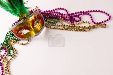 Téléchargez les photos : Composition de perles de mardi gras colorées et masque de carnaval sur fond blanc avec espace de copie. Fête, célébration et concept de carnaval. - en image libre de droit