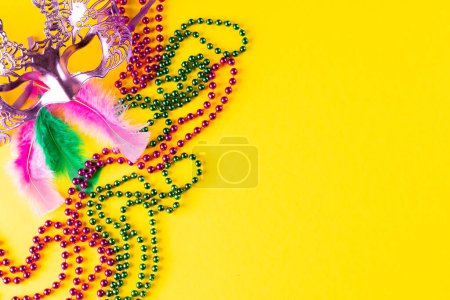 Foto de Composición de coloridas cuentas de mardi gras y máscara de carnaval sobre fondo amarillo con espacio para copiar. Fiesta, celebración y concepto de carnaval. - Imagen libre de derechos