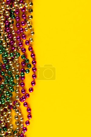 Photo for Composition of colourful mardi gras beads on yellow background with copy space. Party, celebration and carnival concept. - Royalty Free Image
