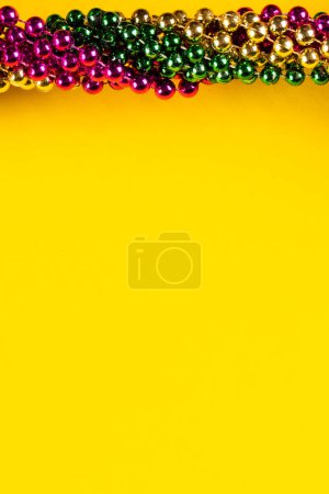 Téléchargez les photos : Composition de perles de mardi gras colorées sur fond jaune avec espace de copie. Fête, célébration et concept de carnaval. - en image libre de droit