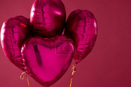 Foto de Cuatro brillantes globos de color rosa en forma de corazón flotando sobre fondo rosa con espacio de copia. Día de San Valentín, amor, romance y concepto de celebración. - Imagen libre de derechos