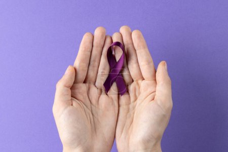 Téléchargez les photos : Mains tenant un ruban de sensibilisation au cancer du pancréas violet sur fond violet avec espace de copie. Services médicaux, santé et sensibilisation à la santé concept. - en image libre de droit