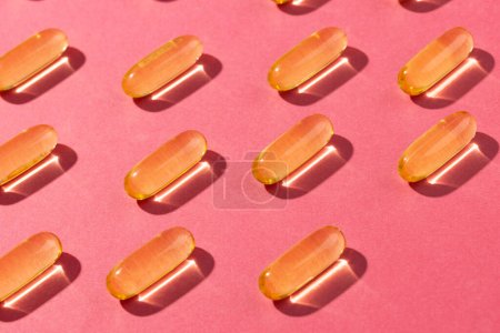Téléchargez les photos : Composition des capsules d'huile disposées en rangées sur fond rose. Médecine, services médicaux, santé et sensibilisation à la santé. - en image libre de droit