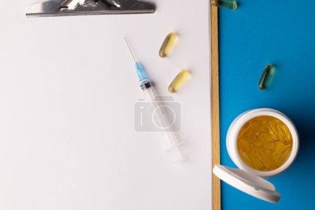 Photo for Composition of clipboard with copy space, syringe and capsules on blue background. Medical services, healthcare and health awareness concept. - Royalty Free Image