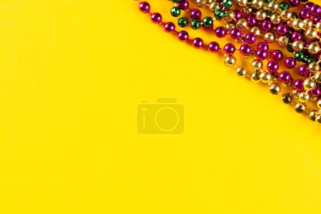 Téléchargez les photos : Composition de perles de mardi gras colorées sur fond jaune avec espace de copie. Fête, célébration et concept de carnaval. - en image libre de droit
