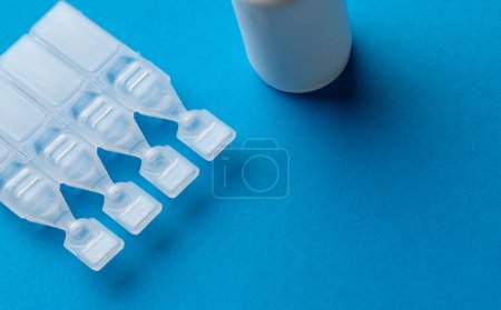 Photo for Composition of saline solution caplets and dropper bottle on blue background with copy space. Medical services, healthcare and health awareness concept. - Royalty Free Image