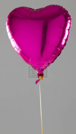 Photo for Vertical of shiny pink heart shaped balloon floating on grey background with copy space. Valentine's day, love, romance and celebration concept. - Royalty Free Image