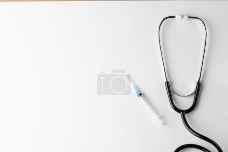 Photo for Composition of stethoscope with syringe on white background with copy space. Medical services, healthcare and health awareness concept. - Royalty Free Image