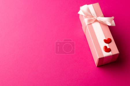 Foto de Caja de regalo rosa pálido atado con cinta blanca y corazones rojos, sobre fondo rosa con espacio para copiar. Día de San Valentín, amor, romance y concepto de celebración. - Imagen libre de derechos
