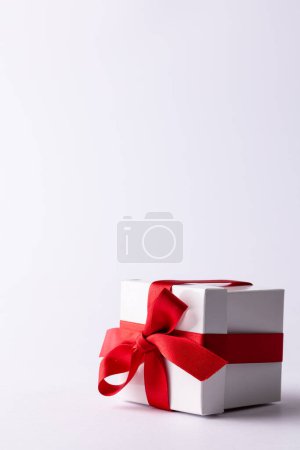 Photo for Vertical of white gift box tied with red ribbon, on white background with copy space. Valentine's day, love, romance and celebration concept. - Royalty Free Image