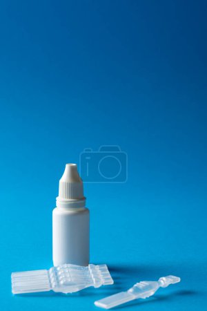 Photo for Vertical of saline solution caplets and dropper bottle on blue background with copy space. Medical services, healthcare and health awareness concept. - Royalty Free Image