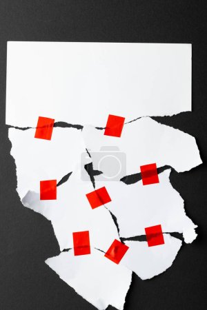 Photo for Ripped up pieces of white paper stuck together with red tape with copy space on black background. Abstract paper texture background and communication concept. - Royalty Free Image