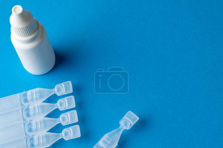 Photo for Composition of saline solution caplets and dropper bottle on blue background with copy space. Medical services, healthcare and health awareness concept. - Royalty Free Image