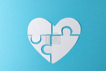 Composition of white heart made of jigsaw puzzle pieces on blue background, with copy space. Medicine, healthcare and health awareness concept.