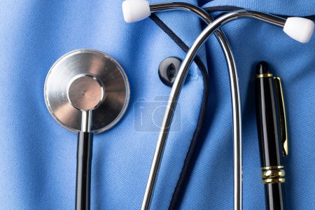 Zusammensetzung aus Stethoskop und Stift auf blauem Krankenschwesterhemd. Medizinische Leistungen, Gesundheitsfürsorge und Gesundheitsbewusstsein.