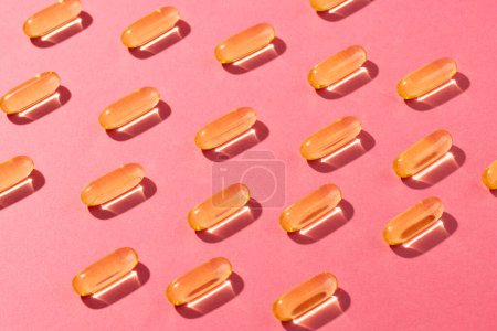 Photo for Composition of oil capsules arranged in rows on pink background. Medicine, medical services, healthcare and health awareness concept. - Royalty Free Image