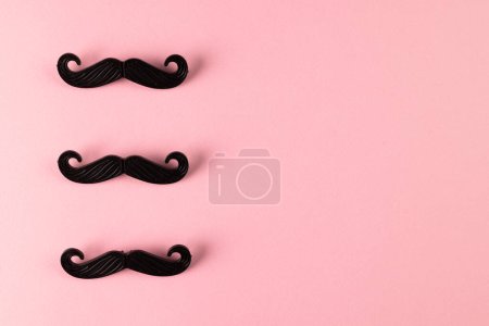 Téléchargez les photos : Composition de fausses moustaches sur fond rose avec espace de copie. Fausse moustache jour, fête, célébration et concept de costume. - en image libre de droit