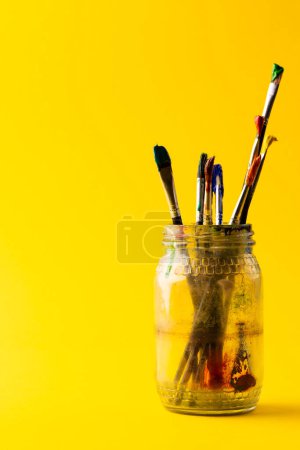 Photo for Composition of jar of painting brushes on yellow background with copy space. National craft month, painting, art and creativity concept. - Royalty Free Image