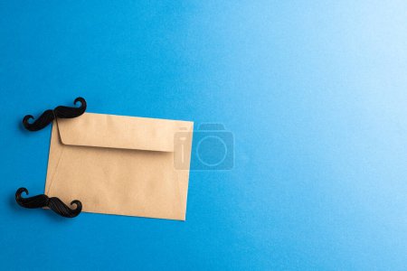 Photo for Composition of fake moustaches and envelope on blue background with copy space. Fake moustache day, party, celebration and costume concept. - Royalty Free Image