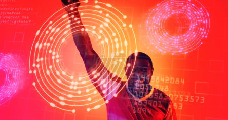 Foto de Jugador de fútbol afroamericano gritando sobre círculos iluminados y lenguaje informático. Compuesto, deporte, competición, jugando, partido, ganador, alegre, codificación, neón, forma y abstracto. - Imagen libre de derechos