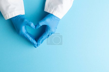 Foto de Manos de doctor usando guantes médicos haciendo forma de corazón sobre fondo azul. Concepto de medicina, salud y ciencia. - Imagen libre de derechos