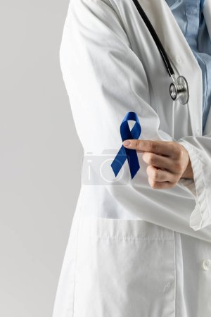 Téléchargez les photos : Partie médiane du médecin caucasien tenant un ruban bleu sur fond gris. Médecine, santé et science concept. - en image libre de droit