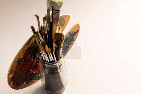 Photo for Composition of jar of painting brushes and palette on white background. National craft month, painting, art and copy space. - Royalty Free Image
