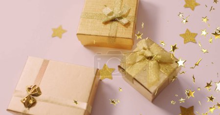 Téléchargez les photos : Plusieurs icônes étoiles dorées flottant contre les cadeaux de Noël sur la surface blanche. Noël fête et concept de célébration - en image libre de droit