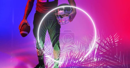 Photo for Low section of american football player holding ball and helmet by illuminated circle and plants. Copy space, composite, african american, sport, competition, illustration, glowing, nature, shape. - Royalty Free Image