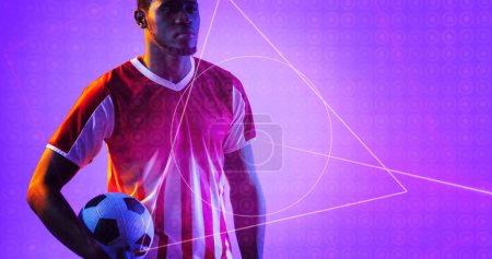 Photo for African american soccer player holding ball by geometric neon design over purple background. Computer graphic, copy space, digital composite, soccer, design, athlete, competitive sport. - Royalty Free Image