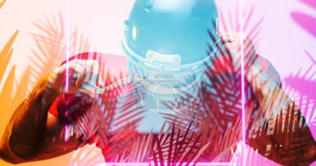 Photo for Close-up of american football player wearing helmet by illuminated square and plants. Composite, sport, protection, competition, illustration, glowing, nature, shape and abstract concept. - Royalty Free Image