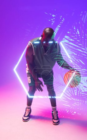 Photo for African american bald basketball player dribbling ball by illuminated hexagon and plants. Copy space, composite, sport, competition, illustration, glowing, nature and shape concept. - Royalty Free Image