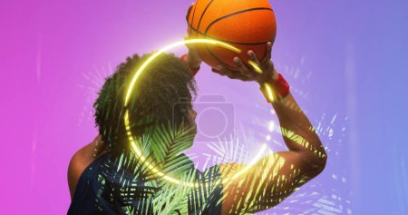 Photo for Rear view of biracial basketball player throwing ball by illuminated plants and circle, copy space. Composite, playing, sport, competition, illustration, glowing, nature, shape and abstract concept. - Royalty Free Image