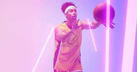 Téléchargez les photos : Composite de joueur masculin biracial jetant le basket-ball sur des lumières éclairées. Copiez l'espace, le sport, le jeu, la compétition, l'illustration, l'éclat, la forme et le concept abstrait. - en image libre de droit