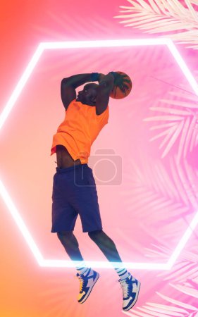 Téléchargez les photos : Un joueur afro-américain de basket-ball qui tire avec une balle sur un hexagone éclairé et des plantes. Copier l'espace, composite, rose, sport, compétition, illustration, lumineux, concept de nature et de forme. - en image libre de droit