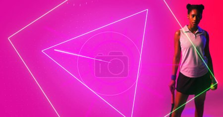 Foto de Jugadora Biracial femenina con raqueta de tenis y pelota de pie por formas geométricas sobre fondo rosa. Iluminado, espacio de copia, compuesto, deporte, competición, partido, forma y concepto abstracto, - Imagen libre de derechos