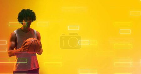 Téléchargez les photos : Composite de joueur masculin biracial tenant le basket par des rectangles éclairés sur fond jaune. Copier l'espace, le jeu, le sport, la compétition, l'illustration, l'éclat, la forme et le concept abstrait. - en image libre de droit