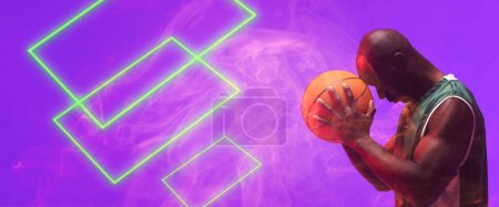 Foto de Vista lateral del jugador de baloncesto afroamericano calvo sosteniendo la pelota por rectángulos iluminados. Compuesto, espacio de copia, violeta, deporte, competición, ilustración, brillante, forma y concepto de humo. - Imagen libre de derechos