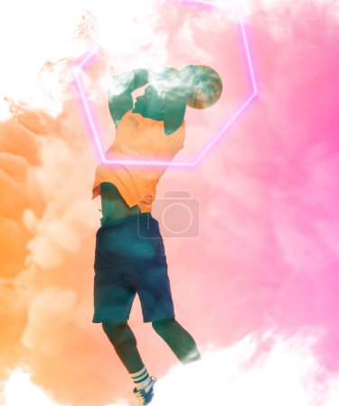 Foto de Jugador afroamericano tomando un tiro con baloncesto por hexágono iluminado sobre fondo ahumado. Compuesto, espacio de copia, rosa, deporte, competición, ilustración, brillante, forma y concepto abstracto. - Imagen libre de derechos