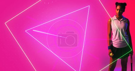 Foto de Jugadora de tenis Biracial femenina con raqueta y pelota de pie por formas geométricas sobre fondo rosa. Iluminado, espacio de copia, compuesto, deporte, competición, partido, forma y concepto abstracto, - Imagen libre de derechos